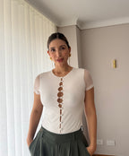 Detalle de la línea de botones al frente del body Luciana blanco para mujer con pantalón verde oliva