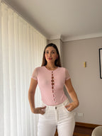 Mujer con body Luciana rosa con botones al frente y mangas en malla, combinado con jean blanco