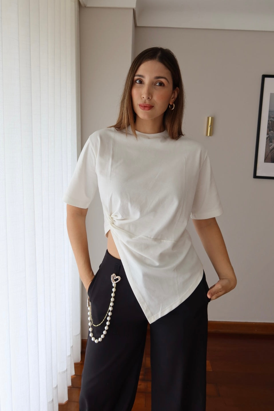 Look con camiseta Lucia blanca de manga corta y nudo al costado, combinada con pantalón negro de tiro alto