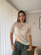 Mujer con camiseta Mila blanca de encaje floral con dobladillo asimétrico y pantalón verde oliva, vista frontal