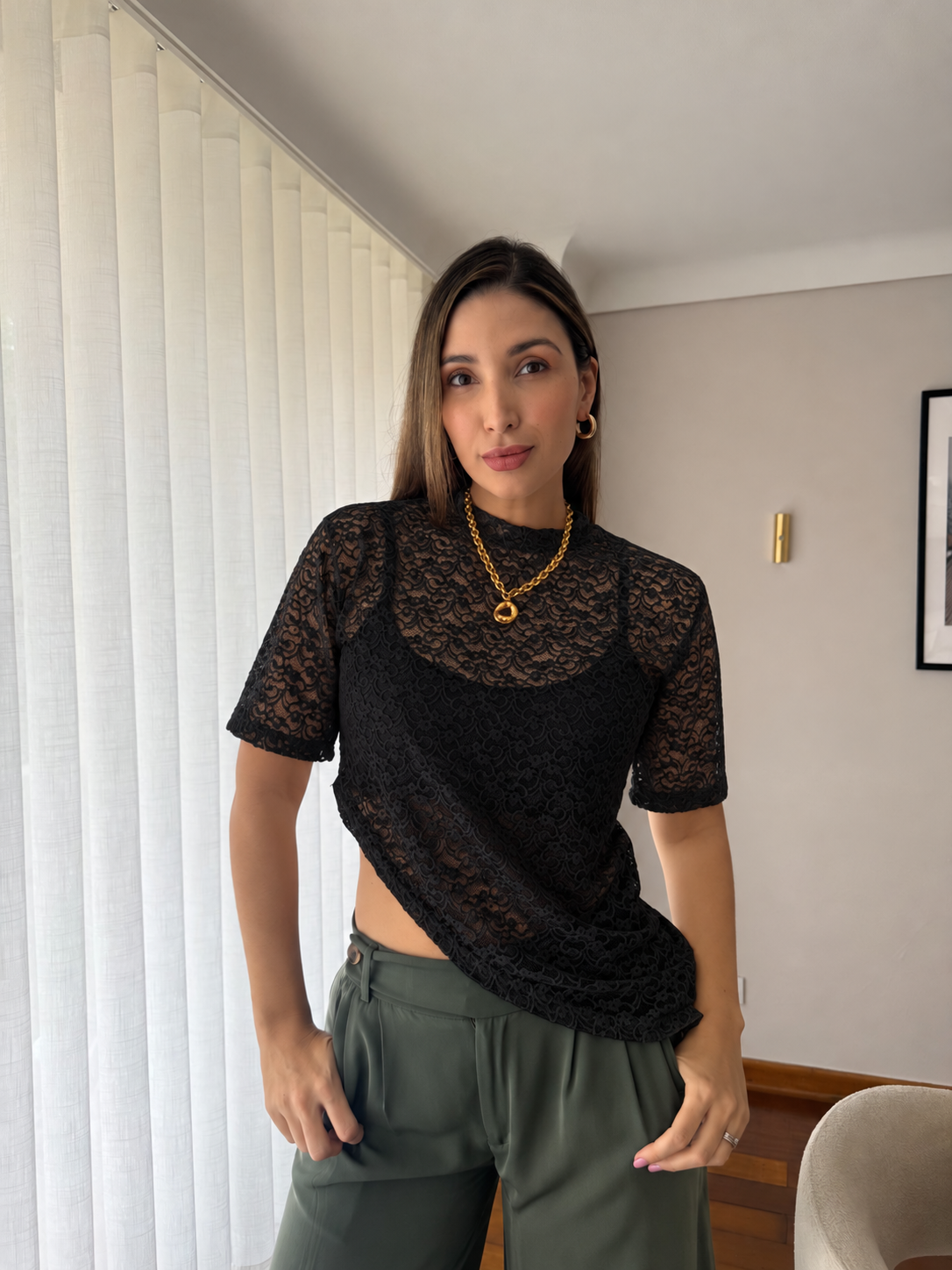 Mujer con camiseta Mila negra de encaje floral con dobladillo asimétrico y pantalón verde oliva, vista frontal