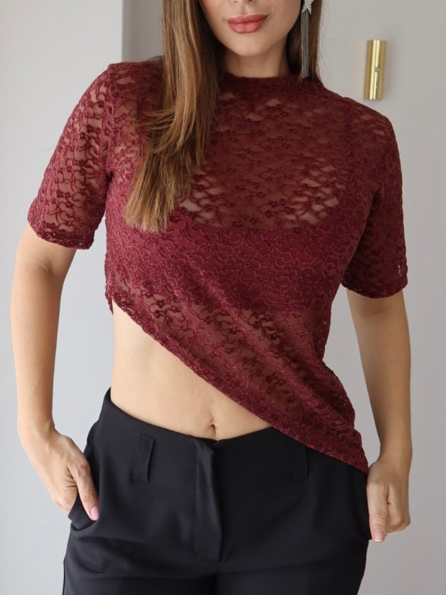 Detalle del encaje floral y el dobladillo en diagonal de la camiseta Mila vinotinto con pantalón negro